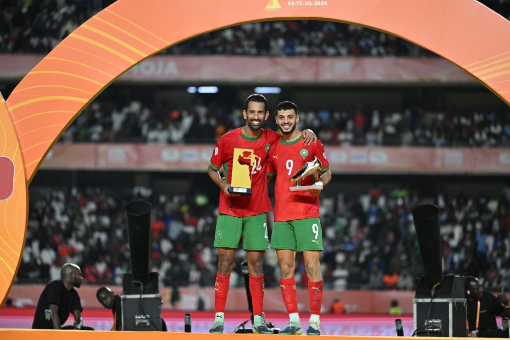 اختارت اللجنة التقنية للكونفدرالية الإفريقية لكرة القدم، على هامش اختتام منافسات بطولة إفريقيا للاعبين المحليين 2025، لاعبين من المنتخب الوطني ليتوجا بجوائز فردية مميزة، تعكس قوة الأداء المغربي في هذه النسخة. وقد تم تتويج اللاعب محمد ربيع حريمات بجائزة أفضل لاعب في البطولة، نظير حضوره المتميز وقيادته المتوازنة لوسط الميدان، وهو ما ساهم في تحقيق المنتخب الوطني نتائج إيجابية قادته نحو منصة التتويج. كما حصل المهاجم أسامة المليوي على جائزة هداف البطولة برصيد ستة أهداف، إضافة إلى جائزة أفضل لاعب في المباراة النهائية أمام منتخب مدغشقر، بعدما بصم على أداء استثنائي وسجل هدفين حاسمين من أصل ثلاثة قادت النخبة الوطنية إلى إحراز اللقب.